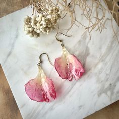 two pink flowers are sitting on a marble surface