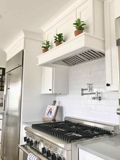 a stove top oven sitting inside of a kitchen next to a refrigerator freezer covered in potted plants