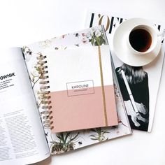 a coffee cup and notebook on top of a table next to an open planner book