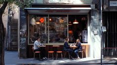 three people sitting at a table in front of a restaurant