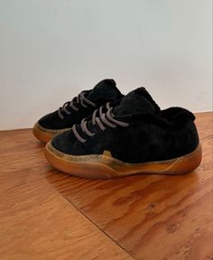 a pair of black and brown shoes on top of a wooden floor