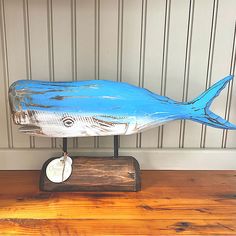 a blue fish statue sitting on top of a wooden table next to a white wall