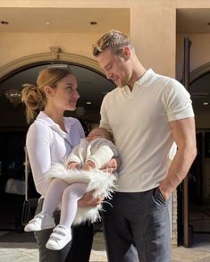 a man standing next to a woman holding a baby