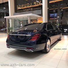 a black car is parked in front of a luxury building with glass doors and windows