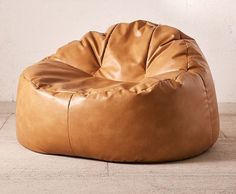 a brown bean bag chair sitting on top of a wooden floor next to a white wall