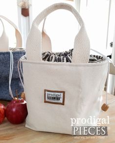 two bags sitting next to each other on top of a wooden table in front of an apple