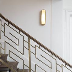 a light that is on the side of a stair case next to a door and some stairs