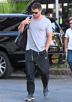 a man is walking down the street while looking at his cell phone and wearing sunglasses