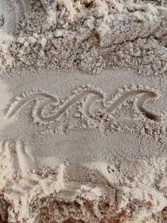 the word love written in sand on top of a sandy beach with waves and swirls