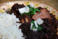 a plate with rice, meat and vegetables on it sitting on top of a wooden table