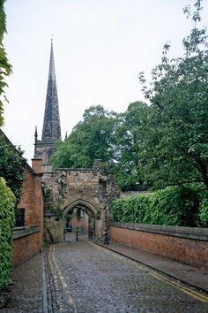 an old brick building with a steeple in the background and cobblestone road leading to it