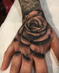 a person's hand with a black rose tattoo on it