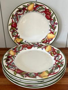 four plates with fruit designs on them sitting on a table