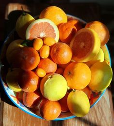 a bowl filled with oranges and lemons on top of a wooden table