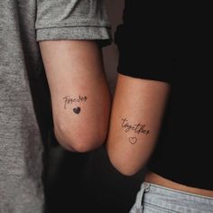 two people with matching tattoos on their arms, one has a heart and the other has a word together