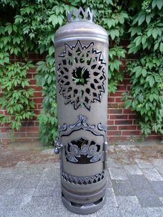 a metal trash can sitting on top of a stone floor next to a brick wall