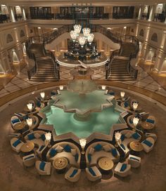 the lobby is decorated with chandeliers and blue chairs in front of a circular pool