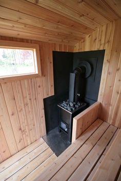 the inside of a sauna with wood paneling and a black stove in it