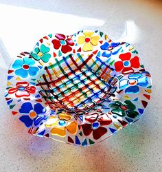 a colorful bowl sitting on top of a table next to a white wall and floor