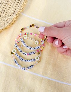 a woman's hand holding several bracelets with words written on them and beads