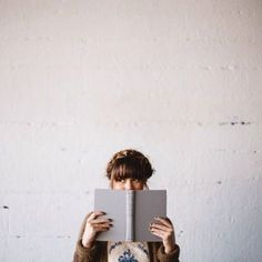 a woman holding up an open book in front of her face