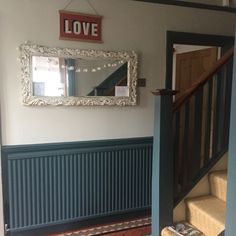 there is a mirror hanging on the wall next to a stair case with a love sign above it