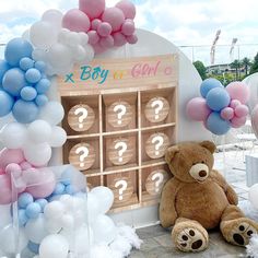 a teddy bear sitting in front of a display with balloons and question marks on it