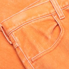 an orange pair of jeans is shown from the waist up, with white stitching on the side