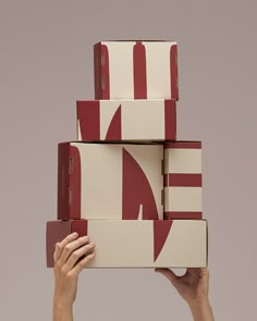 a person holding several boxes on top of each other in front of a gray background