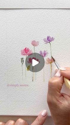 someone is painting flowers with watercolors on paper