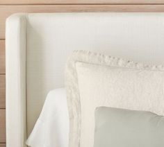 a close up of a bed with white sheets and pillows