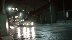 cars driving down the street in the rain at night