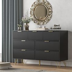 a black and gold dresser with a mirror on it's sideboard in front of a window