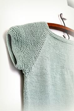 a green sweater hanging on a wooden hanger