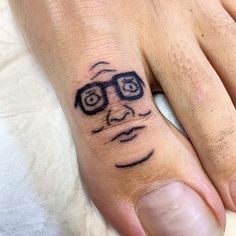 a person's hand with a tattoo on it that has a face and glasses