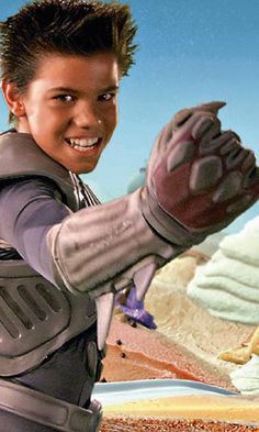 a young boy in a star wars character costume holding up his hand to the camera