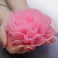 a woman's hands holding a pink flower on top of a gray countertop