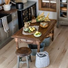 a wooden table topped with fruit on top of a hard wood floor next to an oven