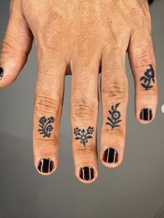 a person's hand with tattoos on it and two fingers in the shape of flowers