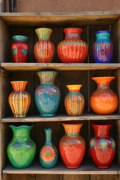 many different colored vases sitting on shelves