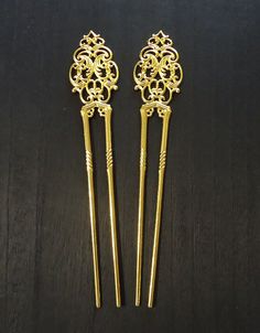 "These Ornate Double Prong Hair Sticks measure approximately 6.5\" Long. The double prong portion that you slide in your hair is 4.5\" Long and the Ornate Design on the top is approximately 2\" Long x 1 1/8\" Wide. Made of Metal Alloy, these sturdy hair sticks have a Bright Yellow Gold Finish.  The open Filigree Design lends itself to easily add embellishments. Choose your quantity from the drop-down menu." Pick Hair, Hair Pick, Bun Holder, U Shaped Hair, Blank Hats, Hair Fork, Ornate Design, Metal Hair, Filigree Design