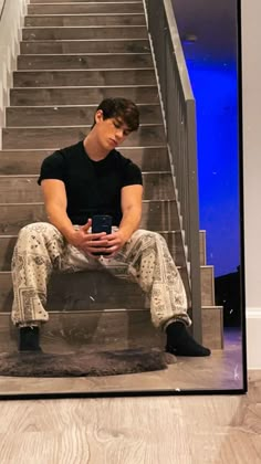 a young man sitting on the stairs holding a coffee cup