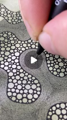 a person is drawing on a piece of fabric with a marker and pen in their hand