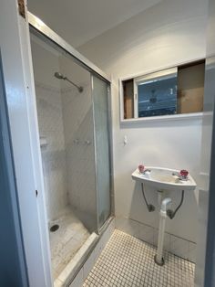 a bathroom with a walk in shower next to a white sink and tiled flooring