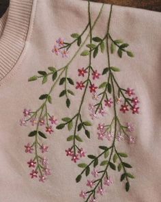 a pink sweater with flowers embroidered on it