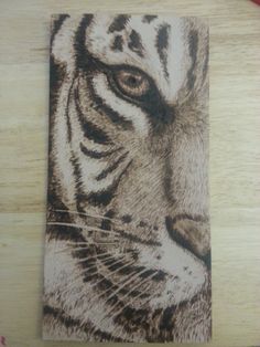 a drawing of a tiger's face on a piece of wood