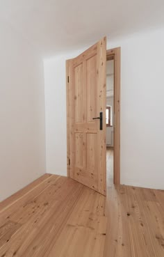 an empty room with wooden floors and two doors that lead to another room in the house