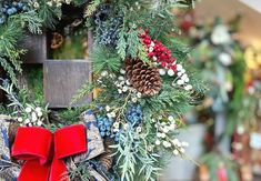 a christmas wreath with red bows and pine cones