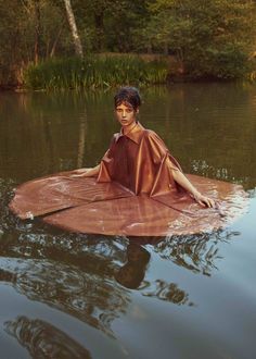 a young boy sitting on top of a body of water with an umbrella over his head