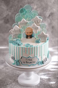 a cake decorated with blue and white icing on a pedestal in front of a gray background